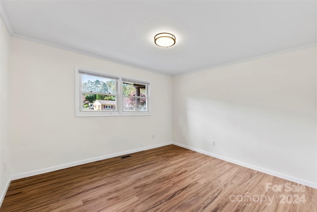 empty room with hardwood / wood-style flooring and ornamental molding