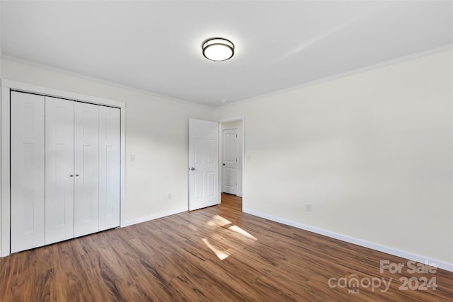 unfurnished bedroom featuring ornamental molding, hardwood / wood-style flooring, and a closet