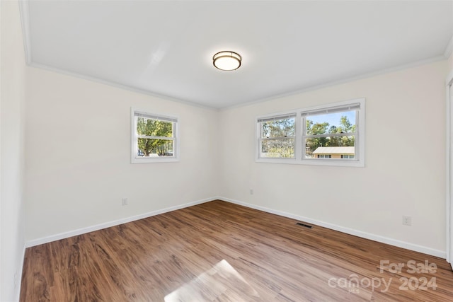 unfurnished room with hardwood / wood-style flooring, a healthy amount of sunlight, and ornamental molding