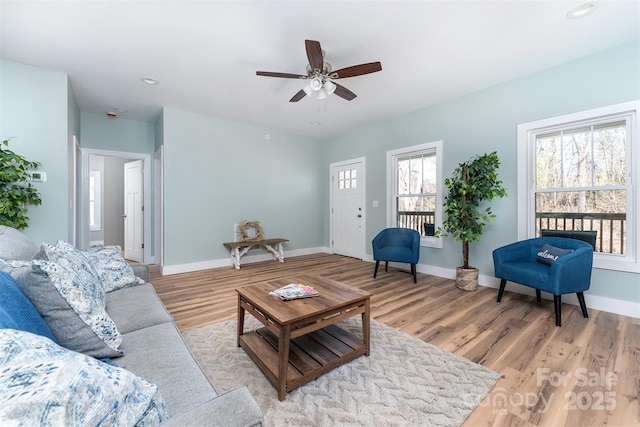 living room featuring light wood-type flooring, ceiling fan, and baseboards