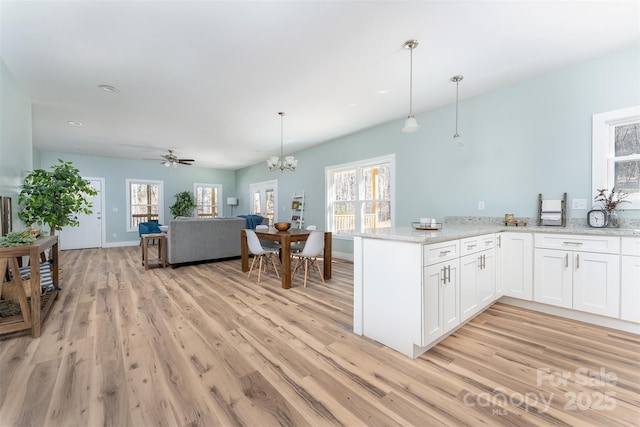 kitchen featuring a healthy amount of sunlight, light wood finished floors, and white cabinetry