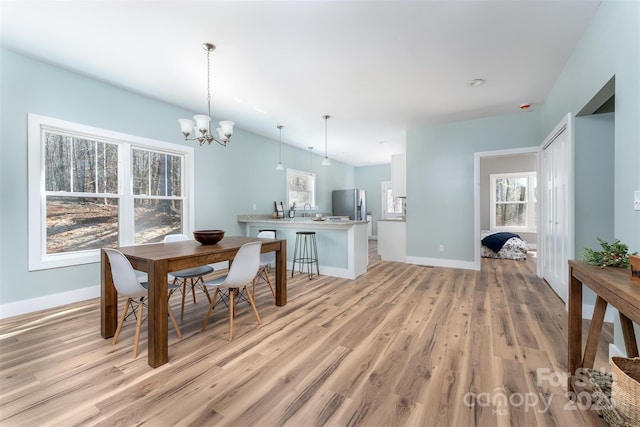 dining area featuring light wood-style flooring, baseboards, and a chandelier