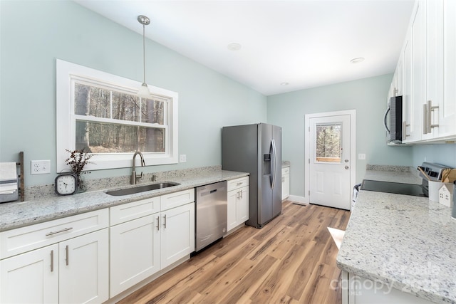 kitchen with light wood finished floors, white cabinetry, stainless steel appliances, and a sink