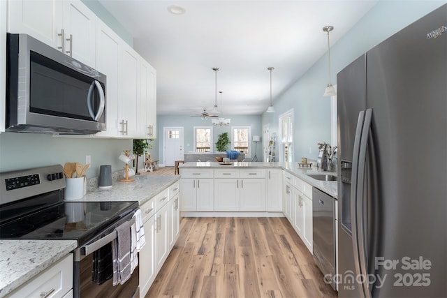 kitchen with open floor plan, appliances with stainless steel finishes, a sink, and white cabinets