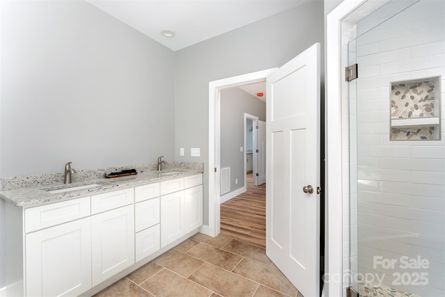 bathroom featuring tile patterned floors, baseboards, a sink, and tiled shower