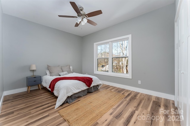 bedroom featuring ceiling fan, baseboards, and wood finished floors