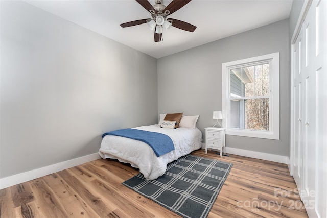 bedroom with ceiling fan, a closet, light wood-type flooring, and baseboards