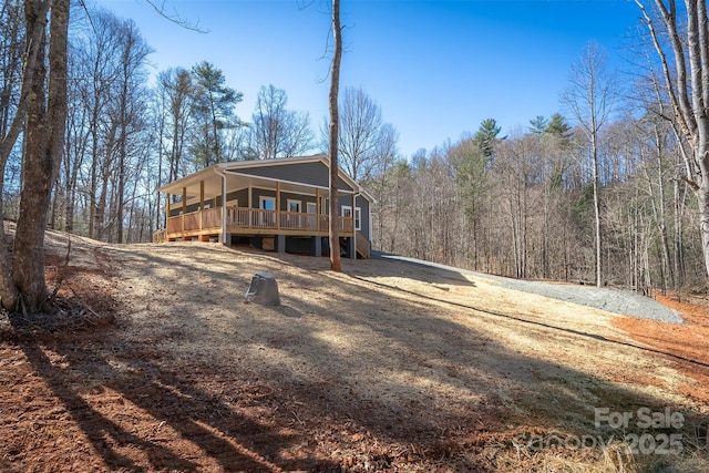 exterior space with stairway, a porch, and a view of trees