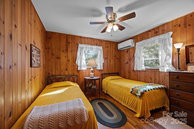 bedroom with wooden walls, multiple windows, a wall unit AC, and wood finished floors