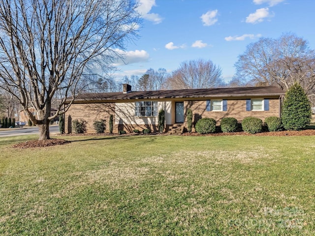 ranch-style home featuring a front yard, brick siding, and a chimney