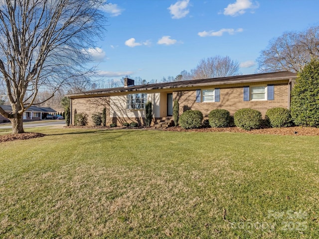 ranch-style home with brick siding, a chimney, and a front yard