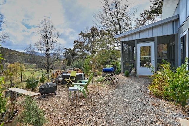 view of yard featuring a sunroom, a mountain view, and a fire pit