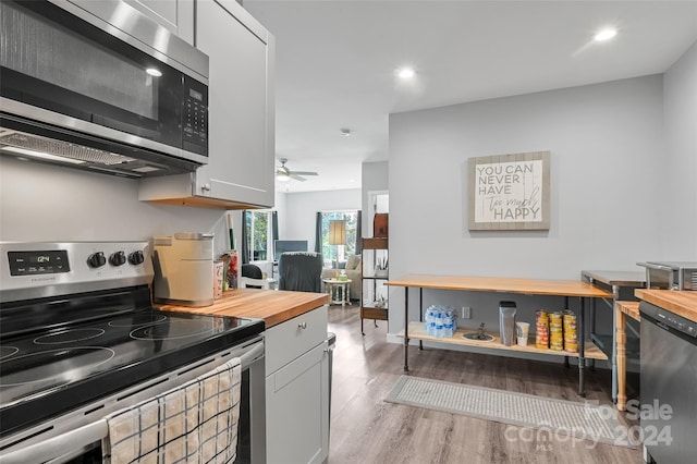 kitchen featuring butcher block countertops, appliances with stainless steel finishes, light wood-type flooring, and white cabinetry