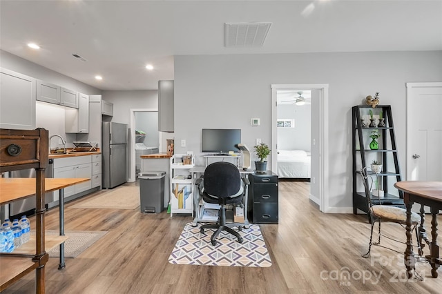 office space featuring sink, ceiling fan, and light hardwood / wood-style flooring