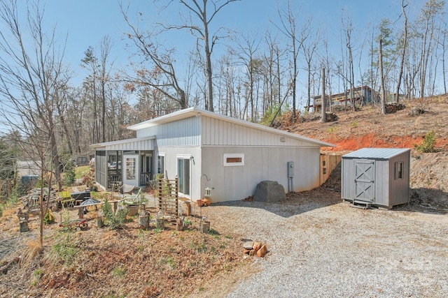 exterior space with a sunroom, a shed, and an outbuilding