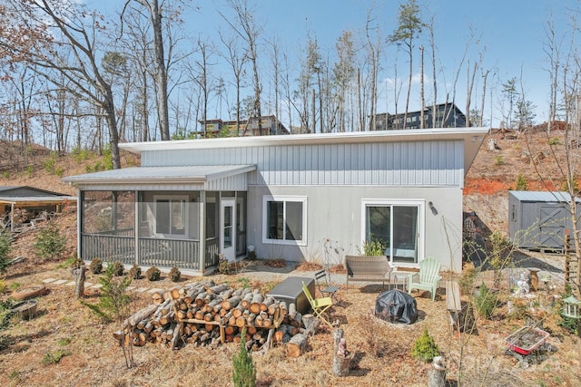 rear view of property featuring a shed, an outdoor structure, and a sunroom