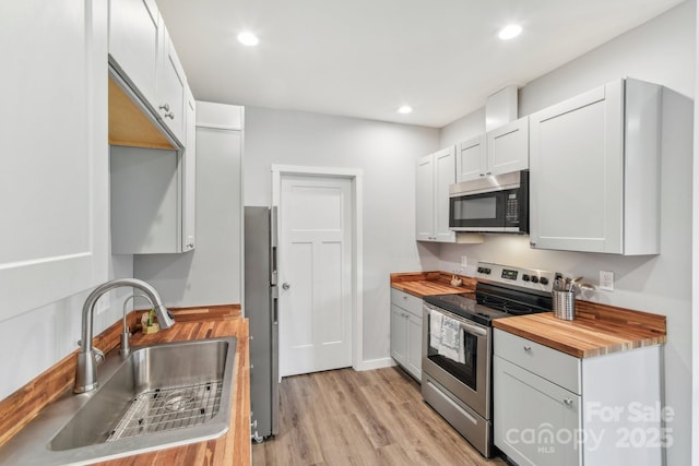 kitchen featuring butcher block countertops, recessed lighting, light wood-style flooring, a sink, and stainless steel range with electric stovetop