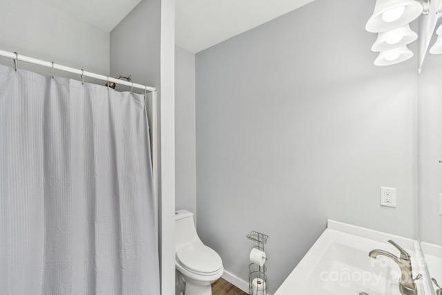 bathroom featuring a shower with shower curtain, a sink, and toilet