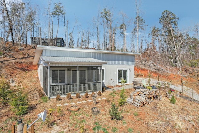 back of house featuring a sunroom, a chimney, and metal roof