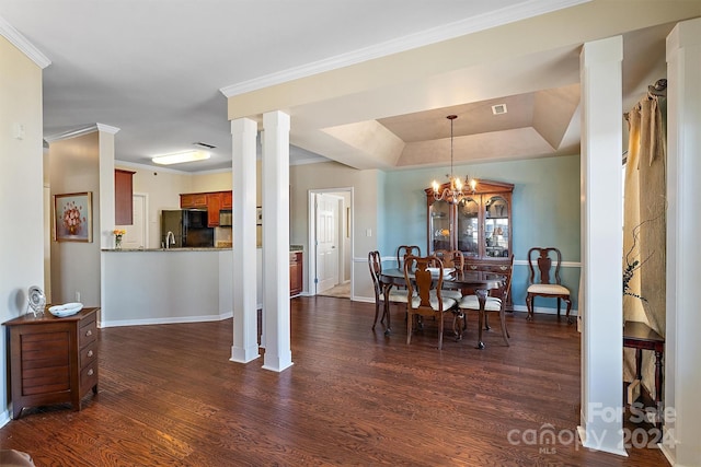 dining space with a tray ceiling, dark wood-type flooring, crown molding, and an inviting chandelier