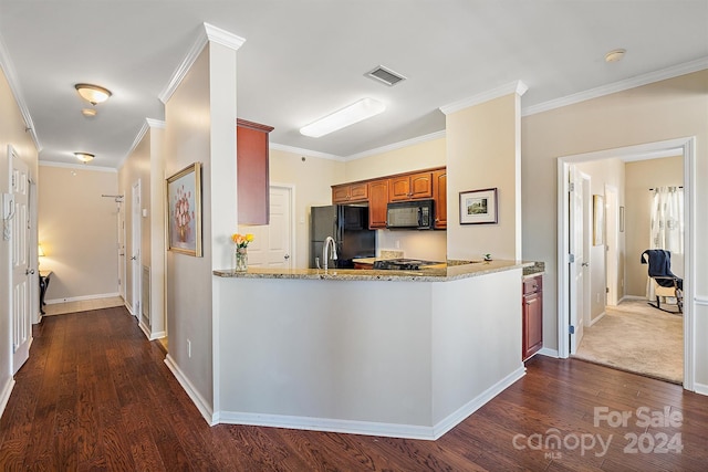 kitchen with light stone counters, ornamental molding, black appliances, and dark wood-type flooring