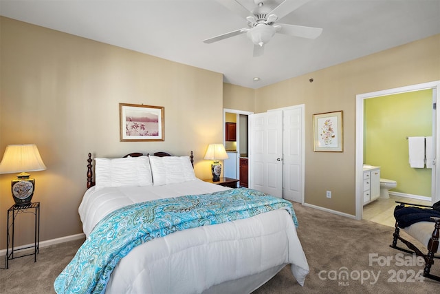 bedroom featuring a closet, ensuite bath, light colored carpet, and ceiling fan