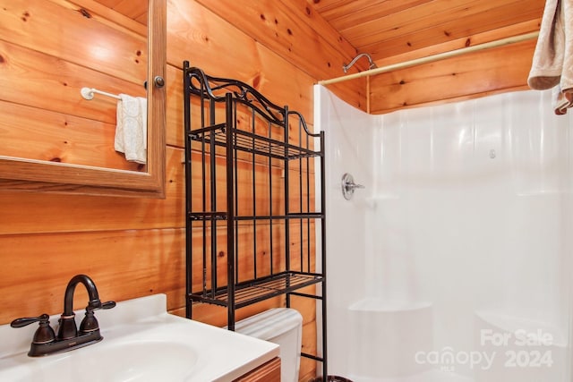 bathroom with toilet, wooden walls, wooden ceiling, vanity, and walk in shower