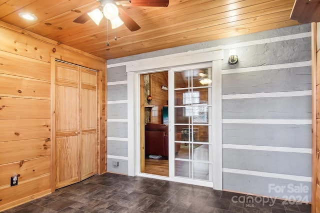 interior space featuring wood walls, wood ceiling, and ceiling fan