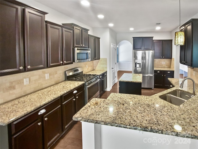 kitchen with decorative backsplash, a kitchen island with sink, stainless steel appliances, sink, and pendant lighting