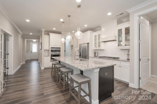 kitchen featuring stainless steel appliances, a kitchen island with sink, white cabinets, pendant lighting, and decorative backsplash