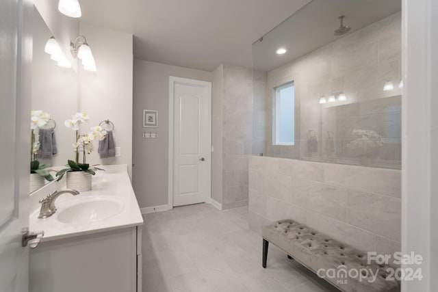 bathroom with tile patterned flooring, vanity, and a tile shower