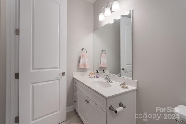 bathroom with toilet, vanity, and tile patterned flooring