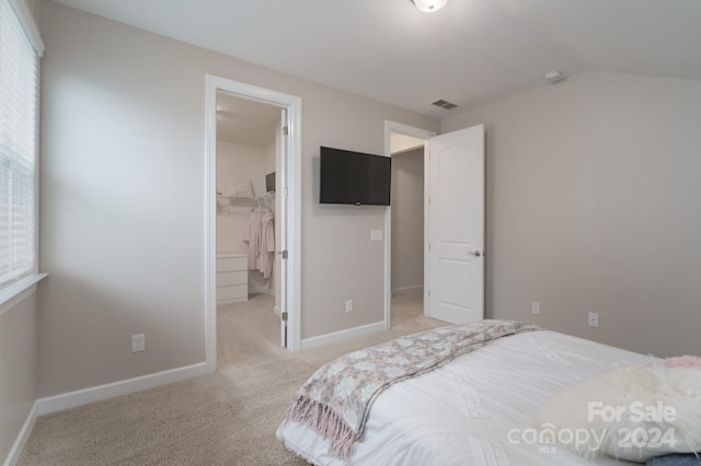 carpeted bedroom with a closet, a walk in closet, and lofted ceiling