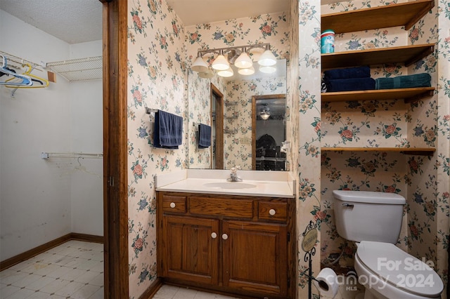 bathroom with toilet, vanity, and a textured ceiling