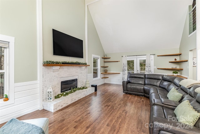 living room with a fireplace, high vaulted ceiling, and hardwood / wood-style floors