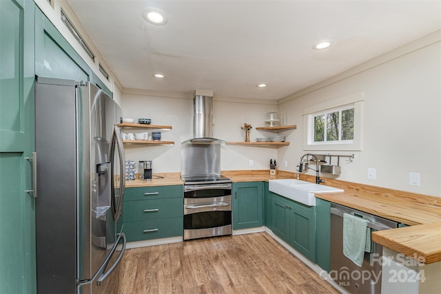 kitchen featuring wooden counters, sink, wall chimney exhaust hood, and stainless steel appliances