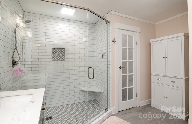 bathroom with hardwood / wood-style floors, a shower with door, vanity, and crown molding