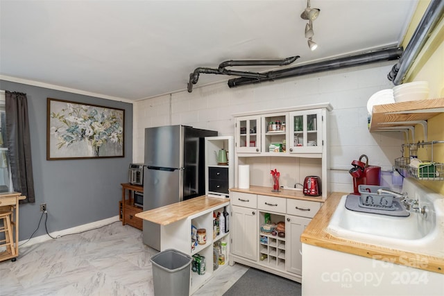 kitchen featuring wooden counters, white cabinets, sink, crown molding, and stainless steel refrigerator