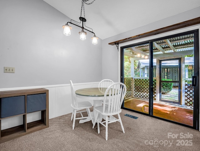 carpeted dining space with lofted ceiling