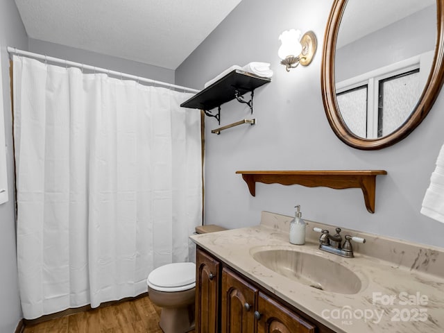 bathroom with hardwood / wood-style flooring, vanity, toilet, and a textured ceiling