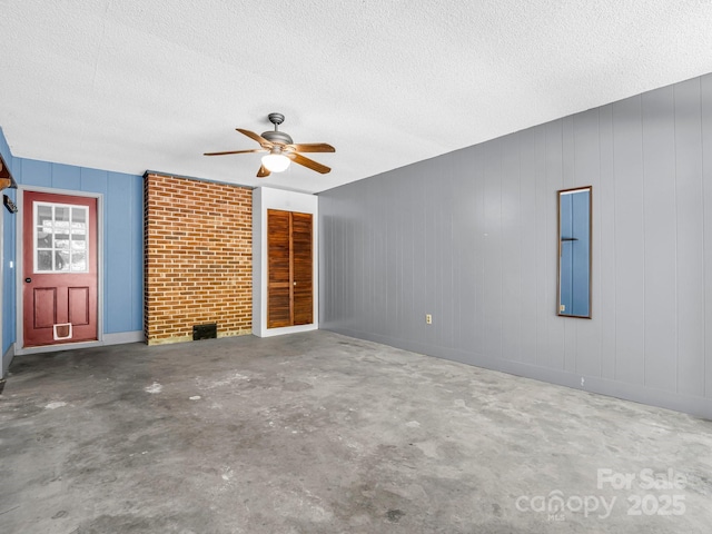 unfurnished living room with ceiling fan, concrete floors, and a textured ceiling