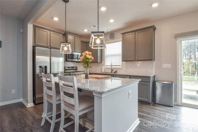 kitchen featuring a wealth of natural light, pendant lighting, appliances with stainless steel finishes, and a center island