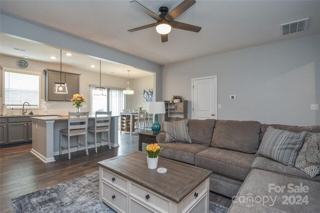 living room with dark hardwood / wood-style flooring, ceiling fan, sink, and a healthy amount of sunlight