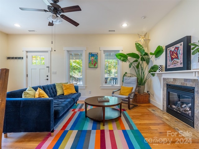 living room with ceiling fan, wood-type flooring, and a tile fireplace