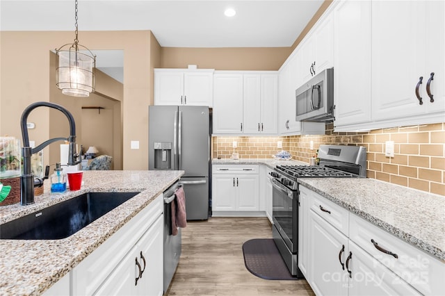 kitchen featuring sink, white cabinetry, hanging light fixtures, and appliances with stainless steel finishes