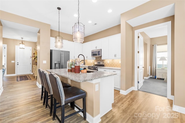 kitchen featuring a kitchen island with sink, white cabinetry, a breakfast bar area, and stainless steel appliances