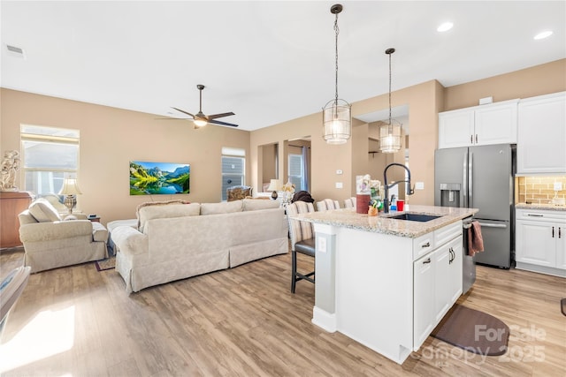 kitchen featuring appliances with stainless steel finishes, light stone counters, white cabinetry, and sink