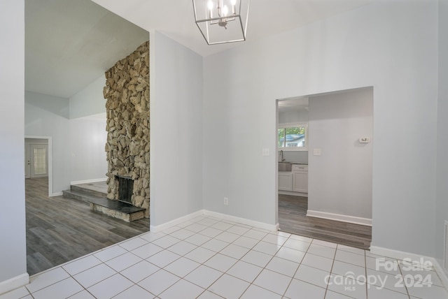 unfurnished living room featuring a stone fireplace, light hardwood / wood-style flooring, and vaulted ceiling