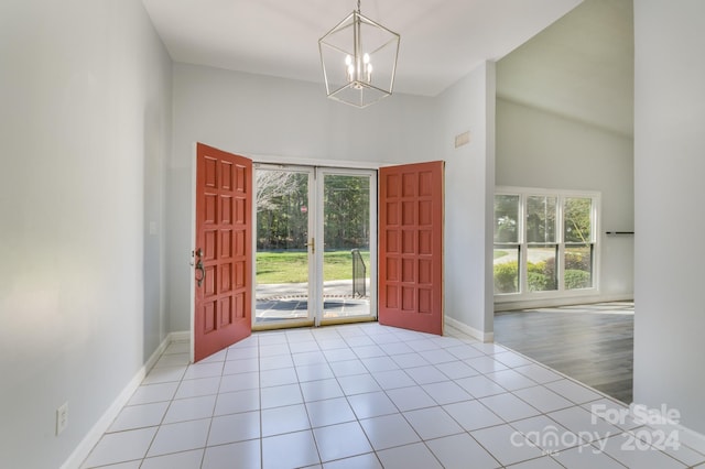 tiled foyer with a notable chandelier and high vaulted ceiling