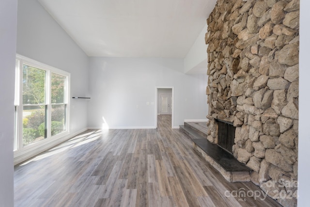 unfurnished living room featuring high vaulted ceiling, wood-type flooring, and a fireplace